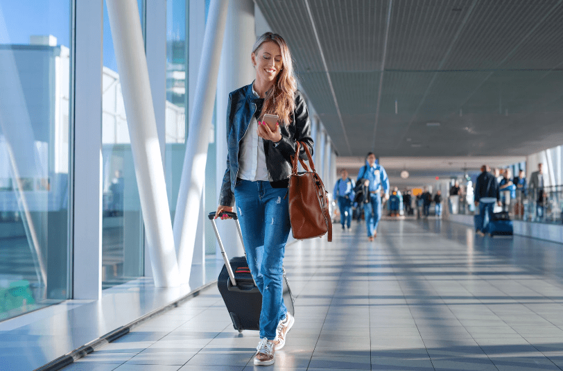 A traveler on her way through the airport satisfied by the personalization she has experienced throughout her travel so far