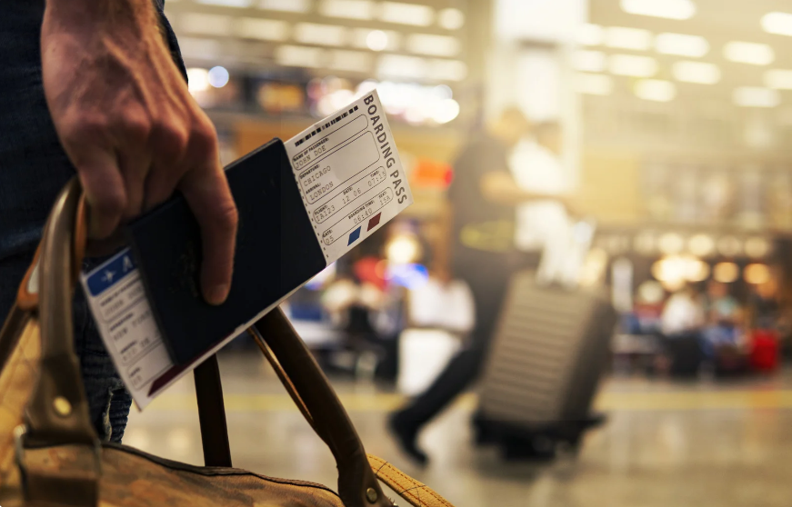 Someone holding a passport and ticket representing travel risk management